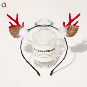 Detail of Christmas reindeer antler headband with red horns and white plush pom-poms