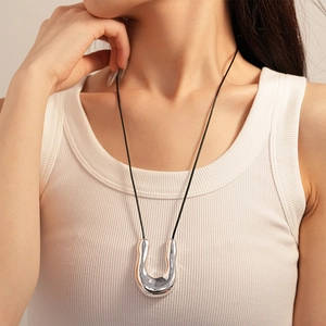 Modern silver liquid metal U-shape pendant necklace with adjustable black cord worn by model