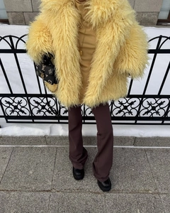 Close-up of yellow faux fur coat texture with warm plush fibers in winter street style