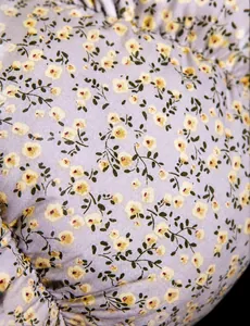 Detailaufnahme von lila Stoff mit gelbem Blumenmuster auf einem Kürbis-Sitzkissen