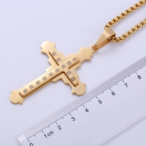 Detailed macro view of a gold double-layered cross pendant with clear cubic zirconia stones
