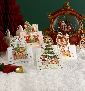 Detailed view of assorted Christmas cards with gold foil patterns on white plush background