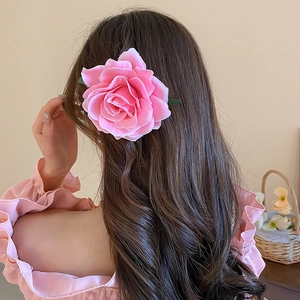 Detailed back view of a pink fabric rose hair clip worn by a model in a sweet style