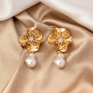 Macro detail of floral earrings with gold petals, crystal center and baroque pearl