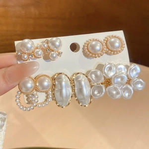 Close-up of elegant pearl and rhinestone stud earrings set on a white display card