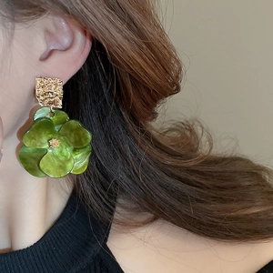 Detail of green floral earring with gold hammered metal square on a model ear