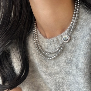 Detail of double-layer dark gray pearl necklace with square crystal clasp on a sweater