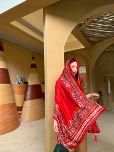 Close-up of ethnic red silk scarf with geometric patterns and fringe tassel details