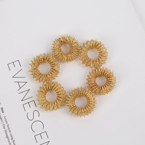 Macro shot of six gold metal spiral finger massage rings arranged in a circular pattern