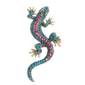 Lizard brooch with blue and pink crystals in golden metal finish on white background