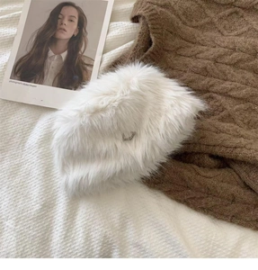 Detail of white faux fur bucket hat with soft plush texture and small metal buckle