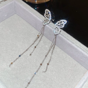 Macro detail of silver butterfly earrings with sparkling zircon and long chain tassels