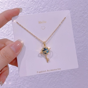 Dettaglio della collana a chiave cielo stellato dorata con pianeta blu e zirconi