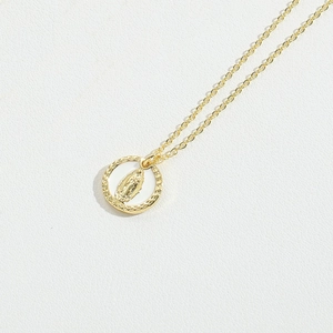 Close-up of golden necklace with a circular Our Lady of Guadalupe relief pendant
