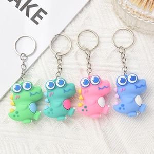 Detailed view of four colorful cartoon dinosaur keychains with metal rings on white fabric