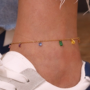 Close-up of gold 18k anklet with colorful zirconia gemstones worn by a model