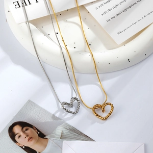 Gold and silver twisted heart pendant necklaces with snake chains on a white tray