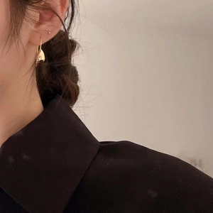 Minimalist gold teardrop earrings for women worn by a model in a cozy setting
