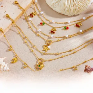 Detail of golden double-layer anklet with cherry, starfish, and dolphin charms on beach sand