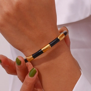 Macro shot of gold and black segmented bamboo bangle worn on a model's wrist