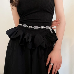 Close-up of vintage silver oval carved metal chain belt on a black dress texture