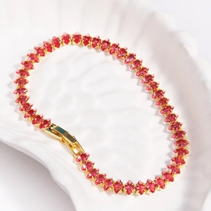 Macro view of gold plated knotted tennis bracelet with marquise-cut red zircon stones