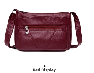 Détail d'un sac bandoulière bordeaux en cuir souple avec des surpiqûres en forme de V