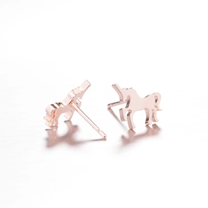 Detail of rose gold unicorn stud earrings on a clean background with soft reflections