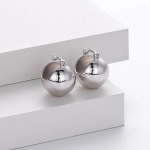 Detailed view of silver spherical earrings on a geometric display stand in minimalist style