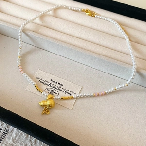 Détail du collier de perles plaqué or 18k avec pendentif sac porte-bonheur sur plateau