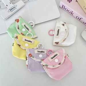 Colorful checkered fabric earphone cases with floral trim and hooks on a desk