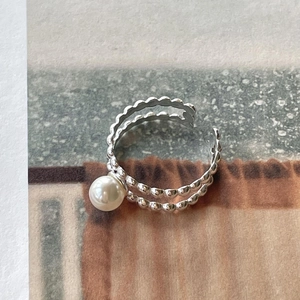 Detail of a double-layered beaded silver ring featuring a round white pearl on stone texture