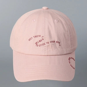 Detailed view of pink cotton baseball cap with dark red embroidered lettering on the front