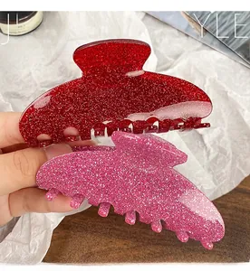 Close-up of large glitter acrylic hair claws in vibrant red and bright pink colors