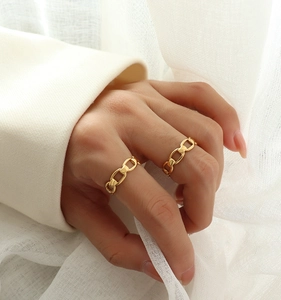 Close-up of gold plated horsebit chain rings worn on fingers with a minimalist style