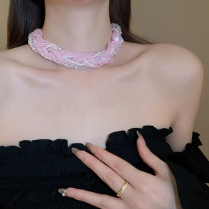 Detailed view of woven pink seed bead and white pearl choker necklace on neck