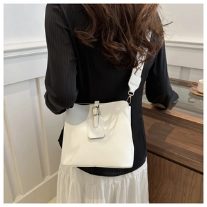 Rear view of a white textured leather bucket bag with gold hardware and wide woven strap