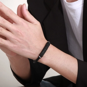 Gros plan d'un bracelet en cuir tressé noir avec tube en métal texturé pour homme
