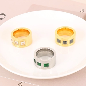 Close-up of luxury titanium steel rings with colorful square zircon stones on a ceramic plate