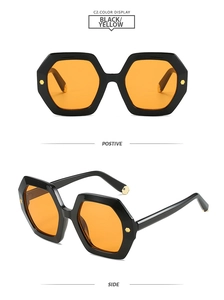 Detail of hexagonal sunglasses with black frame, orange lenses and gold rivet accents