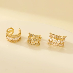 Detailed macro view of three vintage gold-tone ear cuffs with zircon and pearl accents