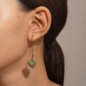 Vue détaillée des boucles d'oreilles vintage cœur et feuille portées par un modèle