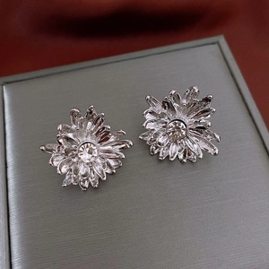 Macro detail of silver floral stud earrings with sparkling center zircon stones