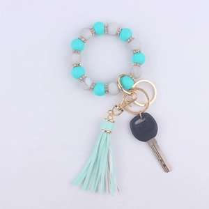 Detail of turquoise and marble silicone bead bracelet with leather tassel and gold keychain