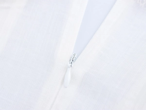 Détail de la fermeture éclair invisible et de la texture en maille sur robe blanche