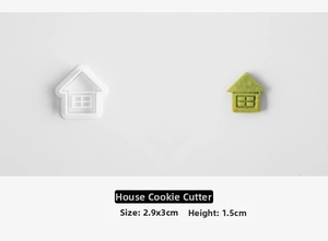 Detail of house-shaped cookie cutter with green embossed biscuit showing window patterns