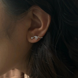 Detailed close-up of 925 sterling silver snake earrings with zircon on woman's ear