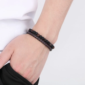 Close-up of men's beaded tiger eye bracelet and brown woven leather wristband on wrist