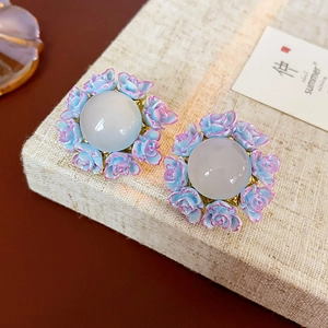 Macro view of blue rose flower cluster earrings with a moonstone-like center gemstone