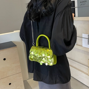 Close-up of lime green sequin crossbody bag with silver chain strap shown on a model